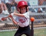 Young boy hitting baseball off of a tee.